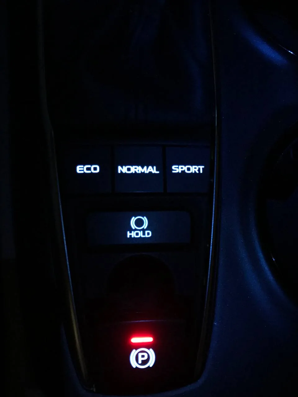 أزرار ECO وNORMAL وSPORT وزر HOLD وزر فرامل اليد عند القير في كامري، مضاءة ليلاً