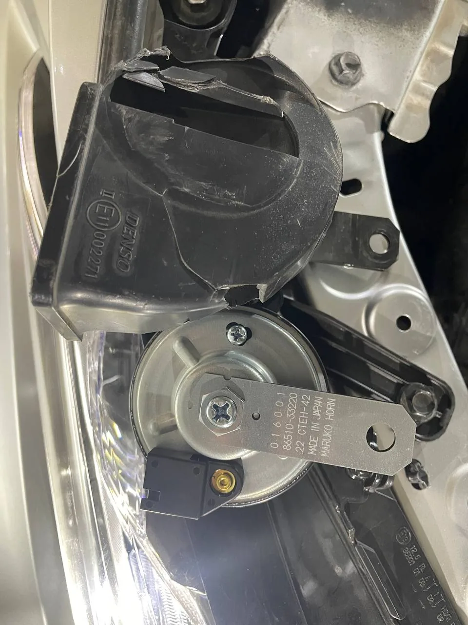 بوري سيارة أسود مكسور عليه كتابة DENSO وتحته بوري فضي برقم 86510-33220 مثبت في مقدمة كامري