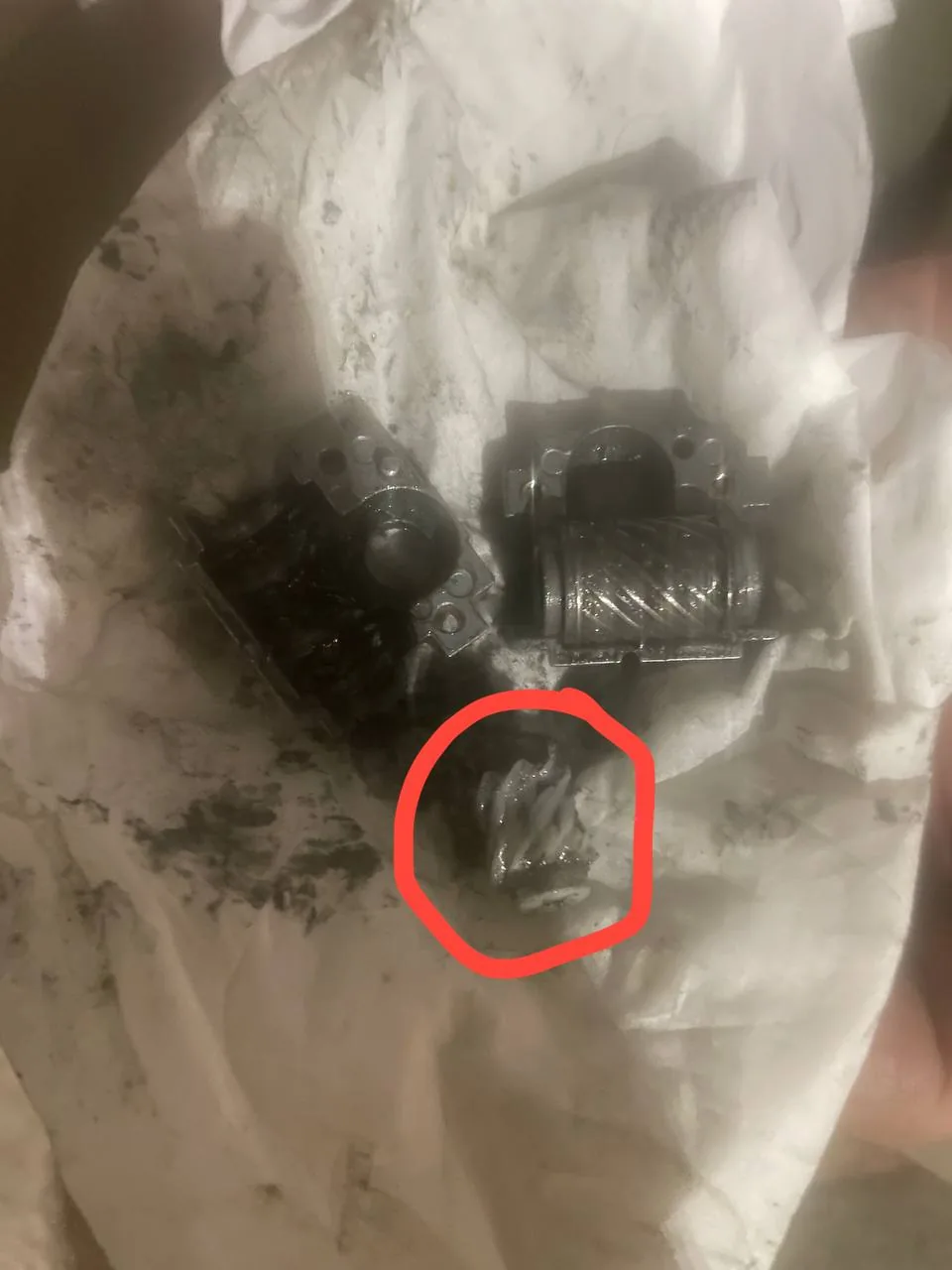 قطع مجرى كرسي كهربائي مفكوكة وعليها دائرة حمراء حول ترس متآكل