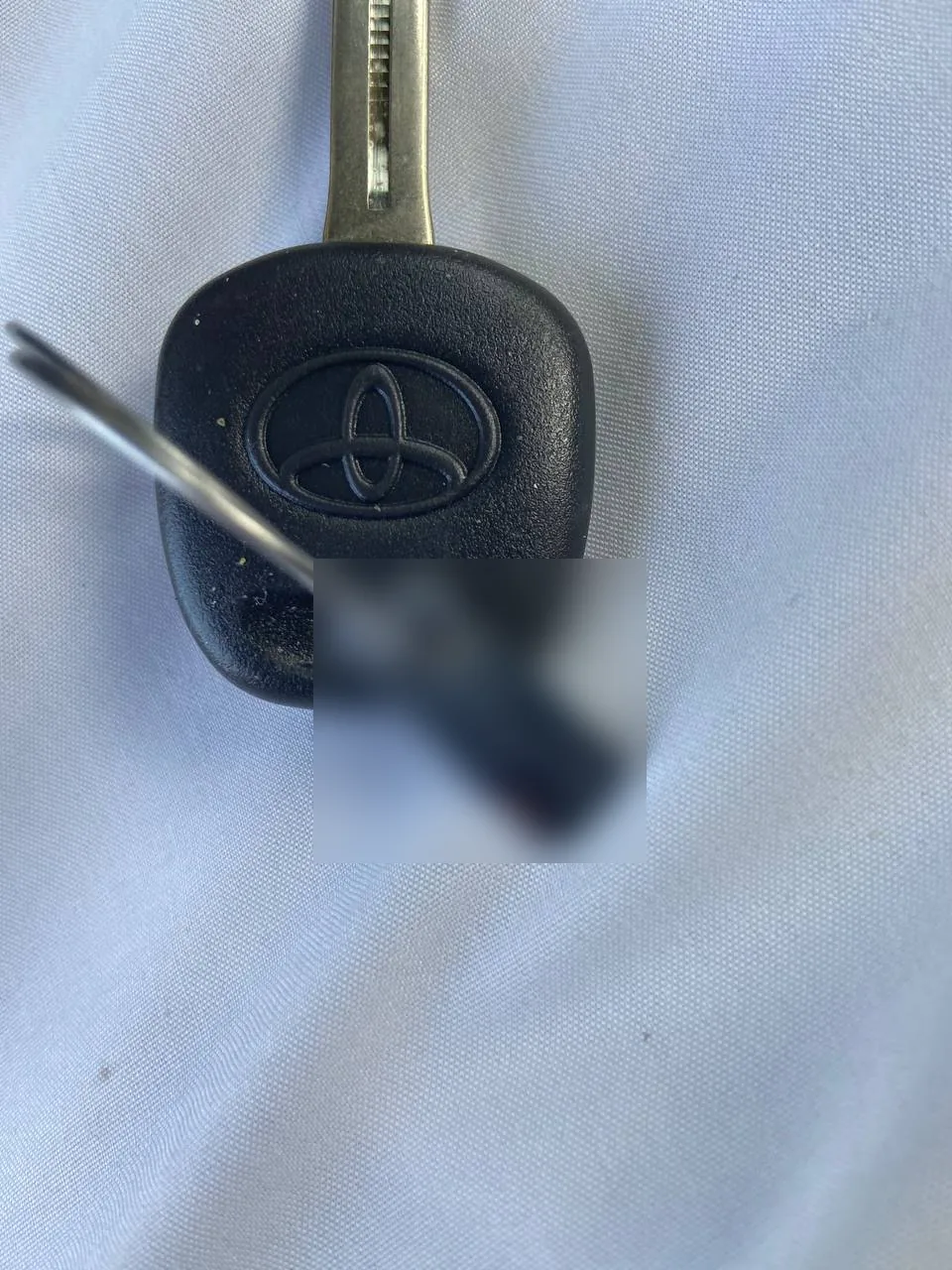 مفتاح تويوتا معلقة به بطاقة معدنية رقمها مموّه